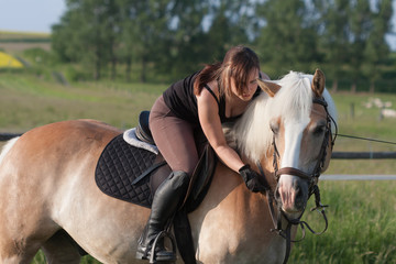 Obraz premium A young woman riding a horse Haflinger