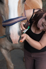 Obraz premium Young girl treats an injured horse´s mouth disinfection.