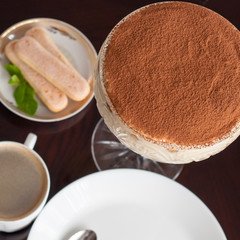 luxurious Tiramisu cake in a glass on a dark background decorated with mint