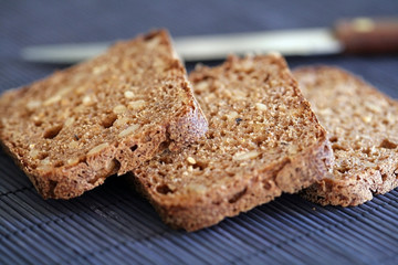 Whole grain bread; bread slices on blue background; close up, selective focus.