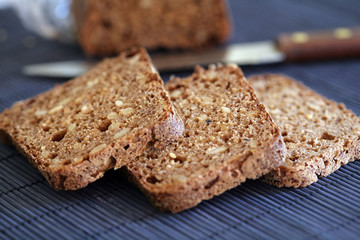 Whole grain bread; bread slices on blue background; close up, selective focus.
