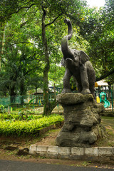 elephant statue standing on rock in front of children playground photo taken in Ragunan zoo Jakarta Indonesia