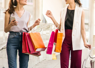 close up, two young happy women talking shopping, sale, consumerism and people concept.