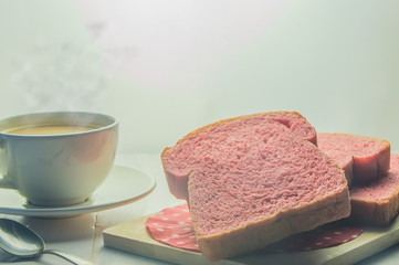 Pink whole wheat bread with espresso coffee on white woodle.