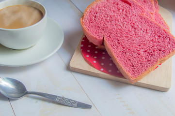 Pink whole wheat bread with espresso coffee on white woodle.