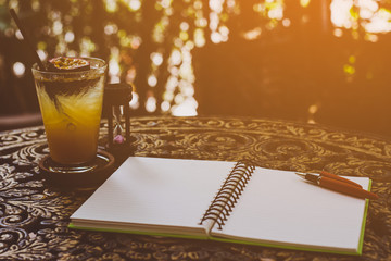 pen and fruit juice on the desk, open a blank white notebook on table