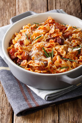 farfaline pasta with tomato, bacon and Parmesan close-up in a saucepan. Vertical