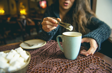 The girl is sitting in a cafe with a cup of coffee