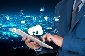 businessmen in blue suite using internet of things on mobile or tablet with night modern city background