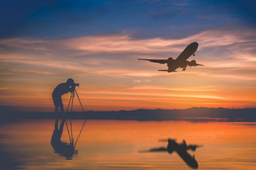Silhouette photographer take photo and silhouette plane fly on sky at sunset in Thailand