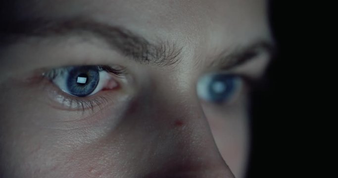 12 years teen puberty eyes looking at the monitor in a dark room,surfing the Internet, close-up