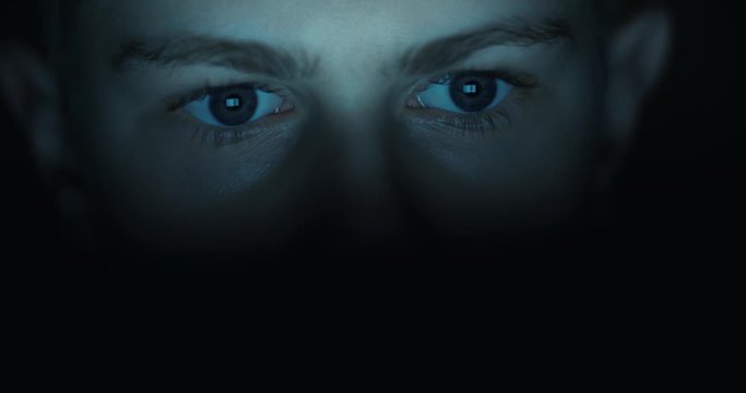 12 years teen puberty eyes looking at the monitor in a dark room,surfing the Internet, close-up