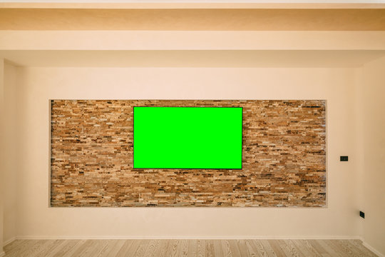 A modern LCD TV with a green screen hanging on the wall.