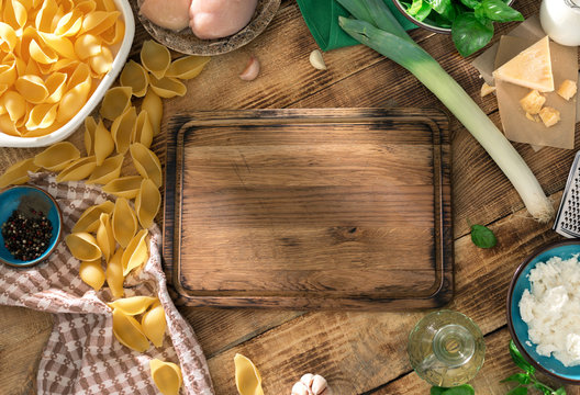 Kitchen board with ingredients for cooking pasta on wooden table