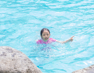 Fototapeta na wymiar Asian Kid (Girl) in Swimming Pool with Finger Pointing
