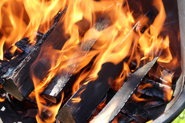 Charred wood and bright flames on dark background