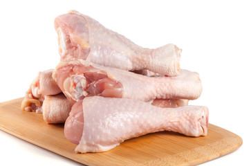 raw chicken drumsticks on a wooden cutting boardn white background