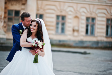 Wedding couple in love stay against old vintage palace.