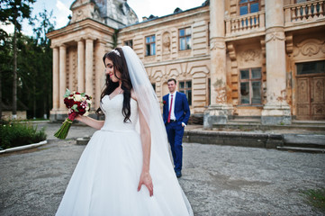 Wedding couple in love stay against old vintage palace.