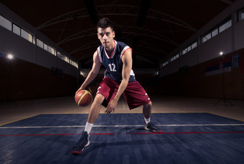 Naklejka premium basketball player dribbling ball thought the legs