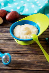 Food for kids, children's lure, organic puree from boiled potatoes in a bowl on a dark rustic wooden background