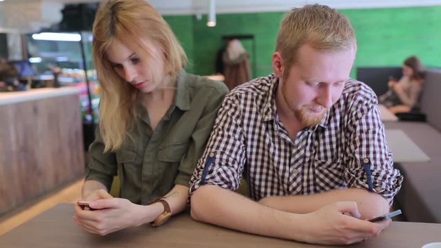Angry couple, each with their phones