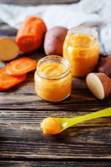 Food for kids, children's lure, organic puree from boiled potatoes and carrot in small glass jars on a dark rustic wooden background   