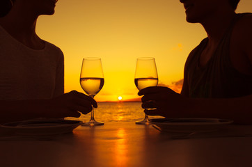 Couple enjoying a glass of wine against a beautiful sunset. 