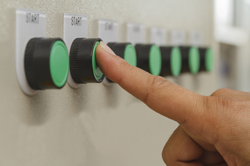 Forefinger finger touch on green start buttons for machine control.