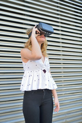 Happy young woman using a virtual reality glasses in a modern metal background