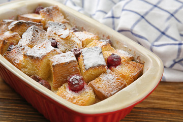 Freshly baked bread pudding in casserole dish on wooden table