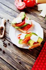 Healthy, wholesome and healthy breakfast or lunch, sandwiches with fresh avocado with spices, mozzarella cheese and tomato on a dark rustic wooden background