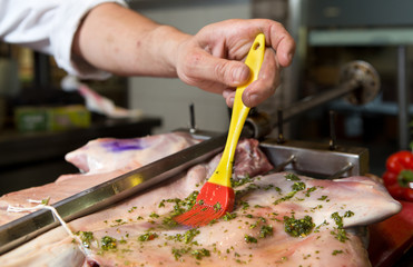 Delicious free range goat shoulder being marinated with parsley and oil, and being prepared for spit roast cooking.