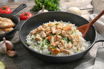 Frying pan with chicken and rice on kitchen table