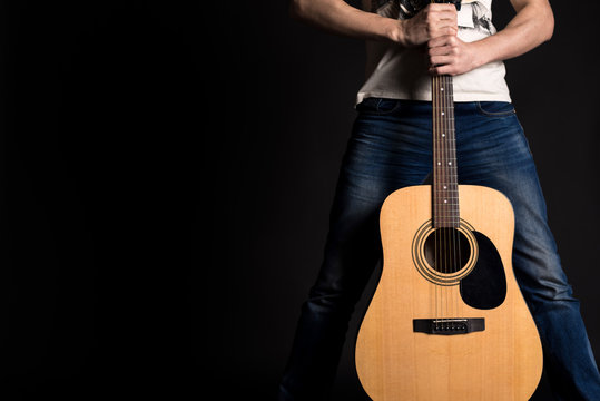 Guitarist holding two hands with an acoustic guitar on a black isolated background