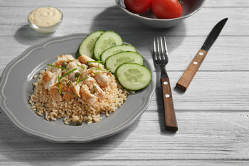 Plate with rice, chicken and vegetables on kitchen table