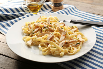 Plate with delicious Chicken Alfredo on wooden table