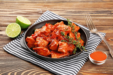 Frying pan with delicious chicken tikka masala on wooden table