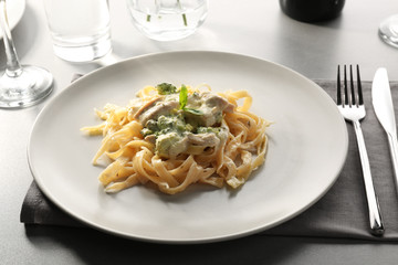 Plate of delicious pasta alfredo with chicken on served table