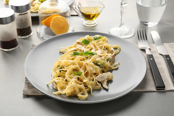 Plate of delicious pasta alfredo with chicken on served table