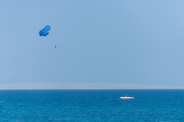 Idyllic blue sea with motor boat and parachute parasailing