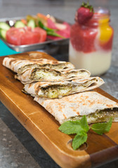 Lebanese manakeesh manouche with zaatar, served on a rustic wooden board with mint leaves and a strawberry smoothie.