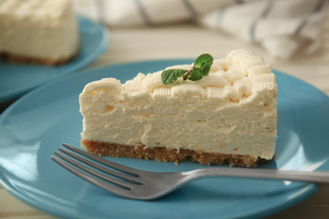 Piece of delicious cheesecake on blue plate