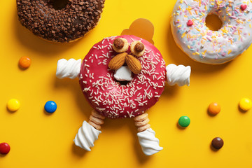 Funny decorated donut on color background