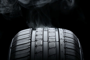 Car tire and smoke on black background