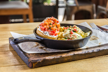 A sandwich with butter and caviar and an omelette in a frying pan on a wooden board