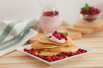 Delicious pancakes with berries and yogurt on wooden table