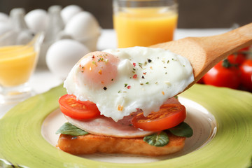 Putting poached egg onto sandwich. Cooking eggs Benedict