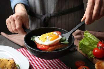 Woman serving egg Benedict for breakfast on table
