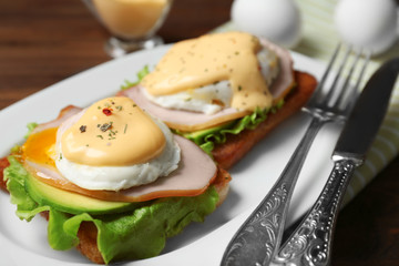 Tasty eggs Benedict on plate, closeup